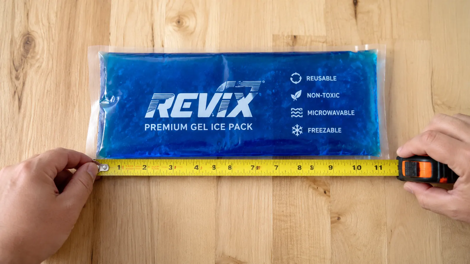 REVIX ice pack laid flat on a wooden surface next to a measuring tape showing its dimensions