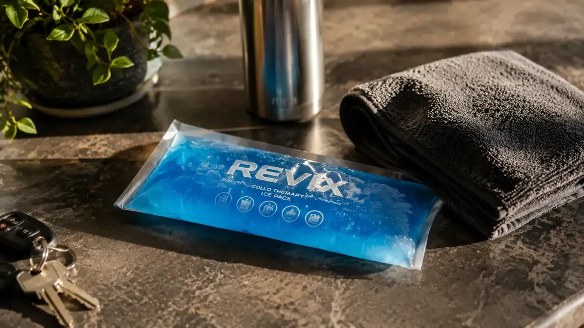 REVIX blue gel ice pack sitting on a countertop next to a gym towel and water bottle