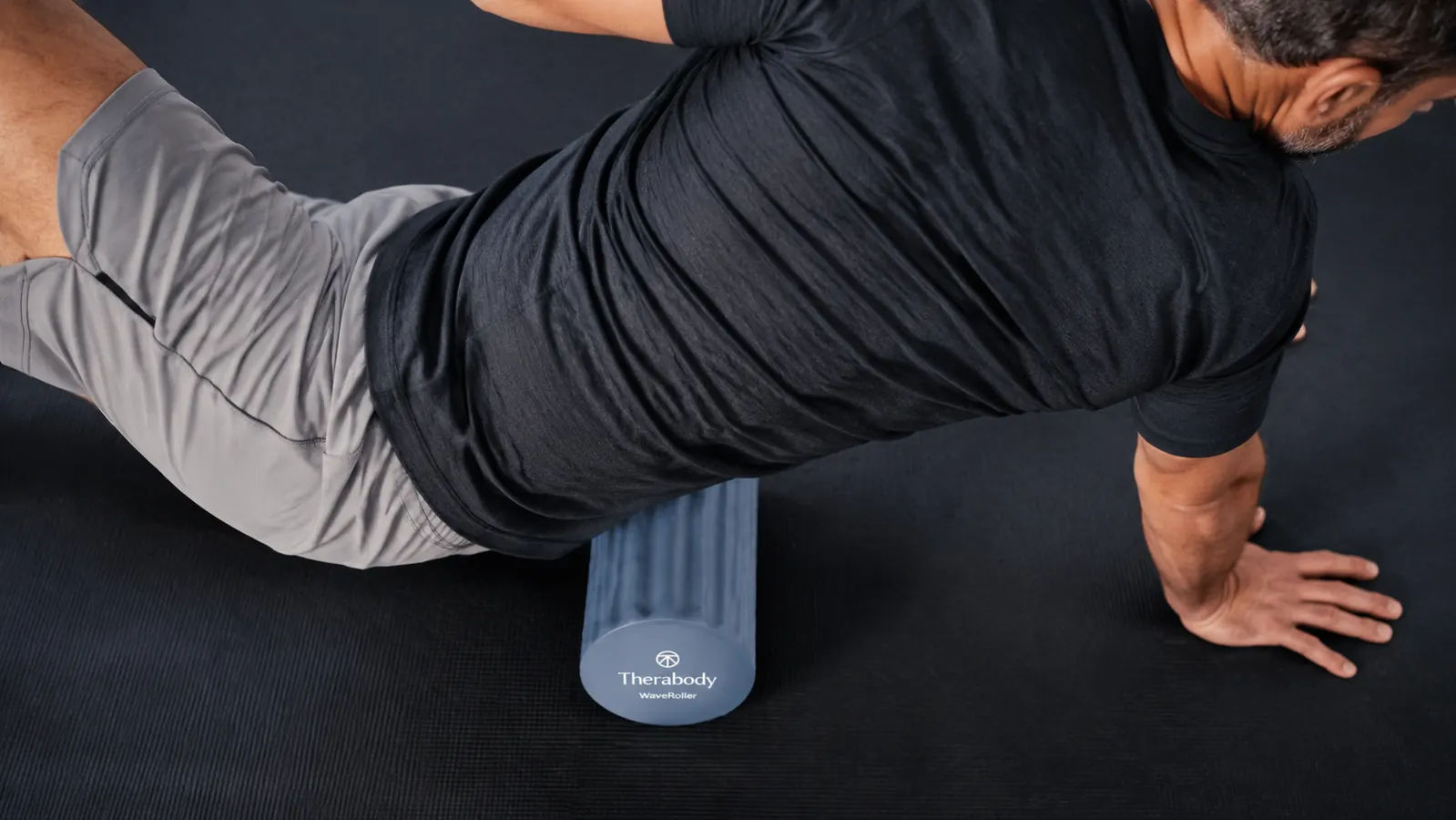 Therabody WaveRoller vibrating foam roller resting on a gym mat next to a water bottle