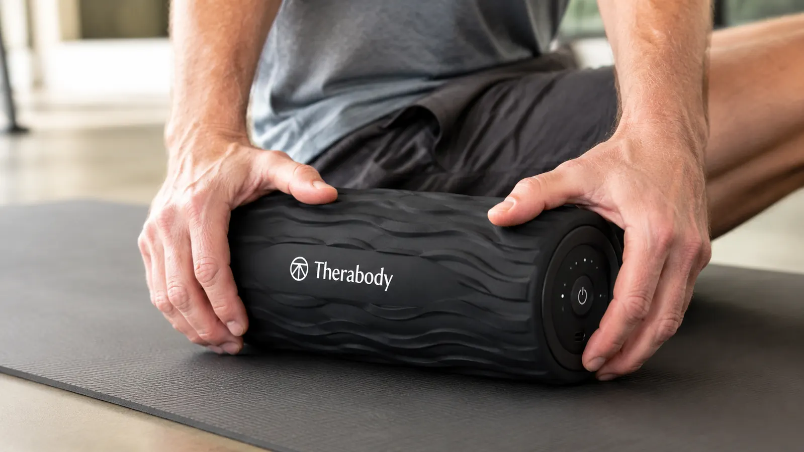 Close-up of hands holding the Therabody WaveRoller showing the control buttons and wave-pattern surface texture